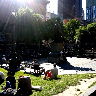 People lay in the sun outside the Melbourne Library
